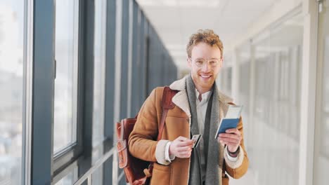 Un-Joven-Feliz-Con-Un-Boleto-Y-Documentos-Camina-Por-El-Pasillo