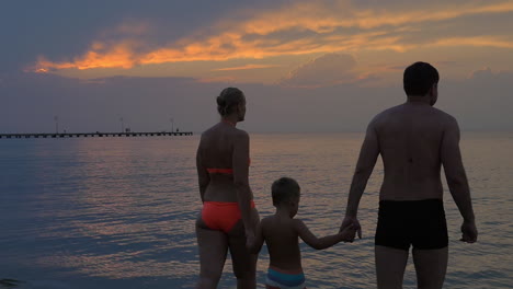 united family going to swim in the sea after sunset