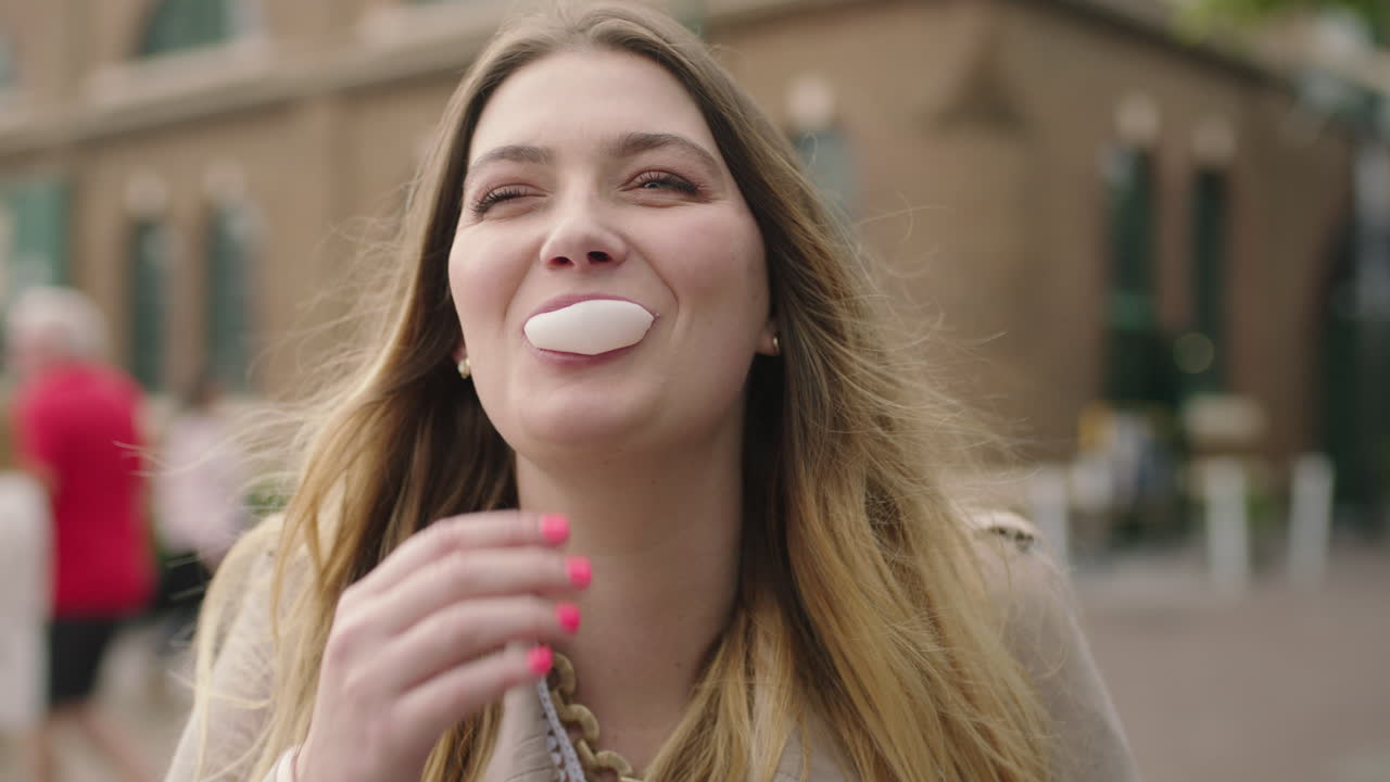 retrato de una joven rubia feliz soplando chicle riendo optimista en el fondo urbano
