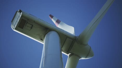 afternoon lower perspective and standing footage from a wind turbine machine's rotating blades