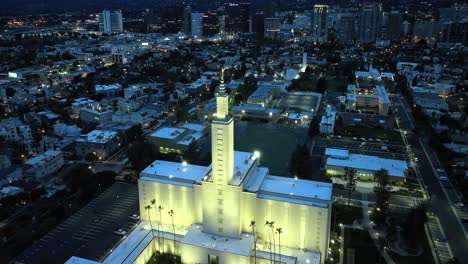 aerial orbit of lds church, los angeles california temple during blue night hour overlooking city