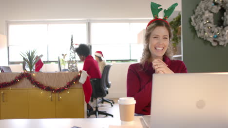 happy caucasian casual businesswoman with reindeer hat making video call at christmas, slow motion