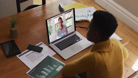 mujer afroamericana que usa una computadora portátil en una videollamada con un colega que trabaja desde casa