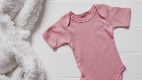 video of pink baby grow and white furry rug with copy space on white background