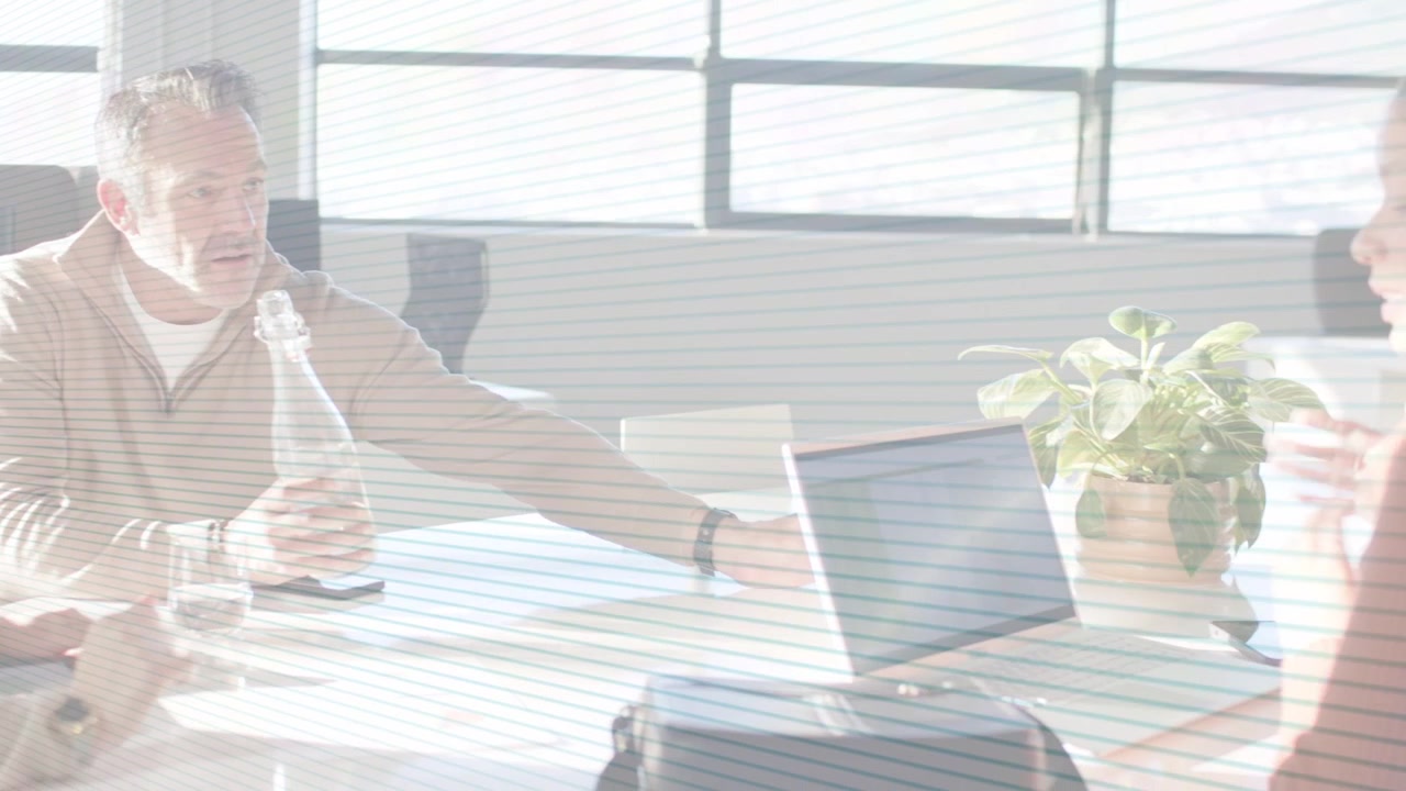 Man reaching toward laptop and offering glass, colleagues responding while discussing business data
