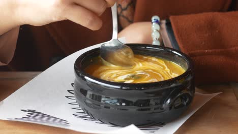 primer plano de una mujer comiendo sopa de calabaza
