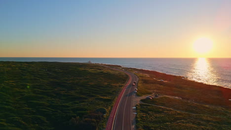 golden ocean sunset view drone. aerial cars riding beautiful sea coast road.