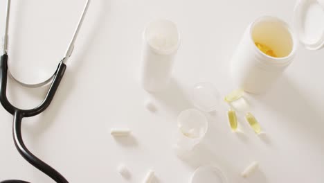 video of stethoscope, pill boxes, pills and capsules on white background with copy space