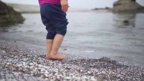 niño descalzo caminando hacia las tranquilas aguas del océano en vacaciones de verano