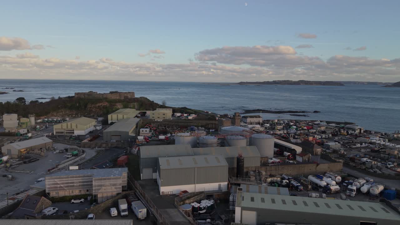St Sampson Guernsey drone footage from Vale Castle over industrial area to harbour and docks with ship berthed at dusk with Herm and Little Russell Channel in the background