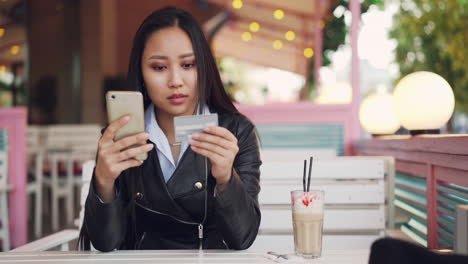 Woman using mobile phone and credit card in a cafe