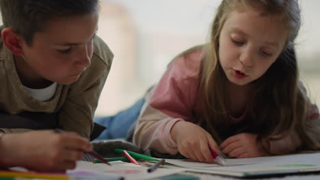 children drawing sketchbooks at home. cute siblings chatting in living room.