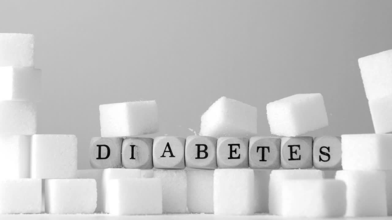 Terninger der staver "diabetes" vælter over sukkerknalder i sort-hvid