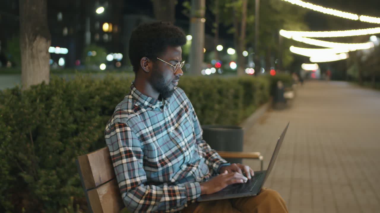 African American Man Using Laptop in Park in Evening