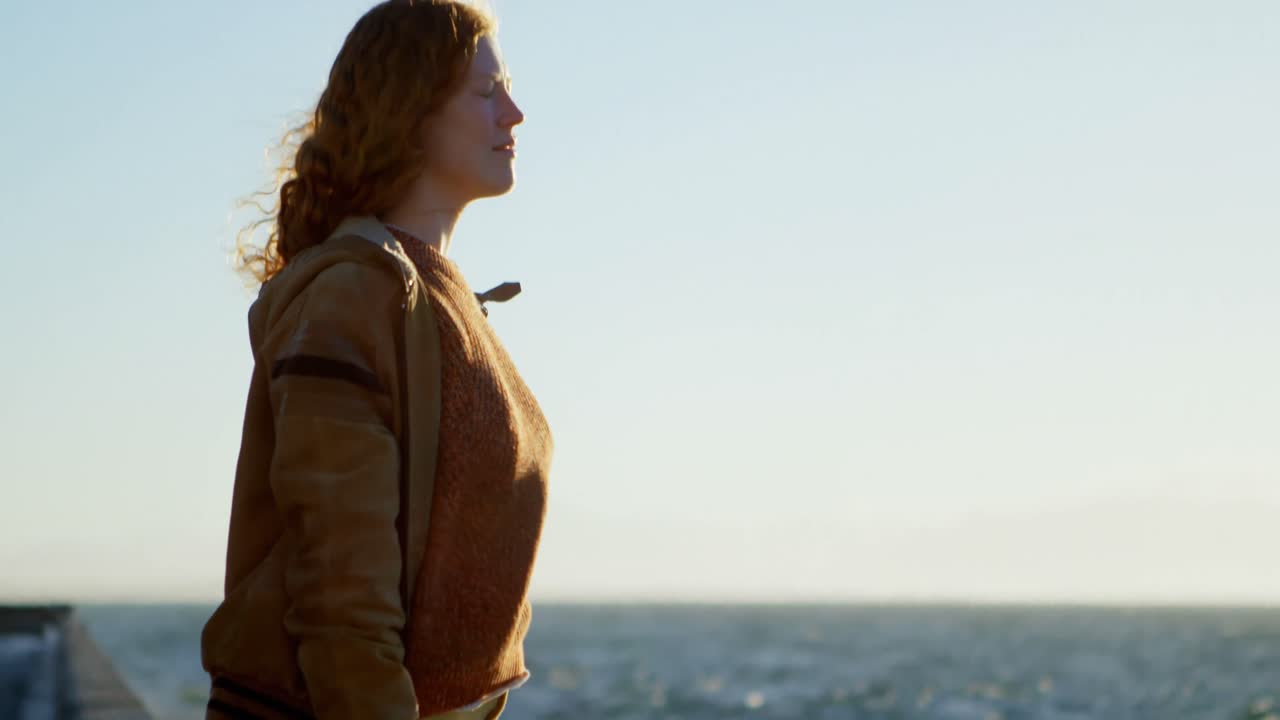 mujer de pie con los brazos extendidos en la playa 4k