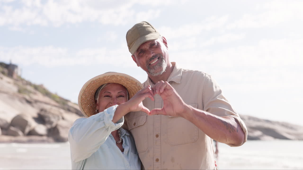 feliz, corazón y manos con una vieja pareja en la playa
