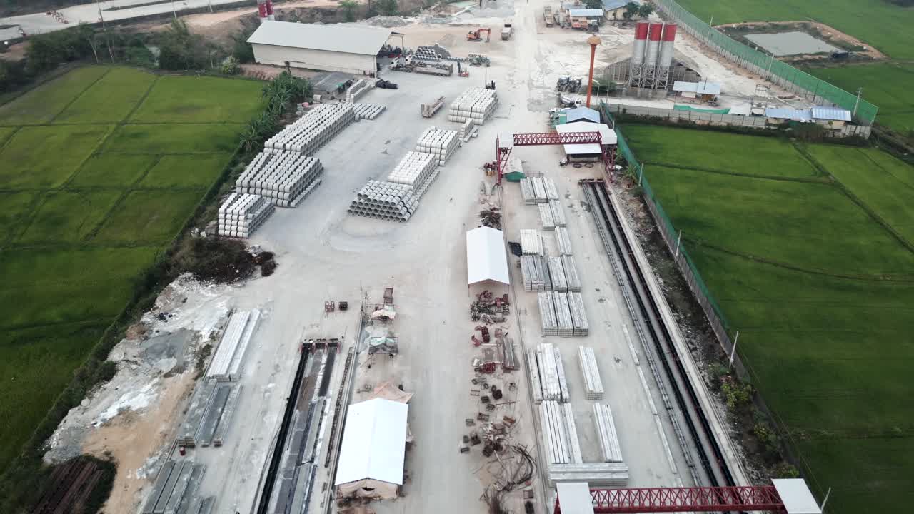 Aerial view of a precast concrete manufacturing and storage facility adjacent to green rice fields