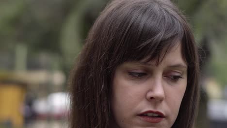 Close-up-of-the-upset,-worried-young-brunette-woman-in-overcast-day