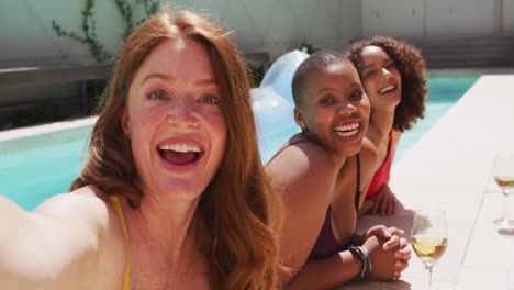 diverse group of female friends having fun at pool taking selfie