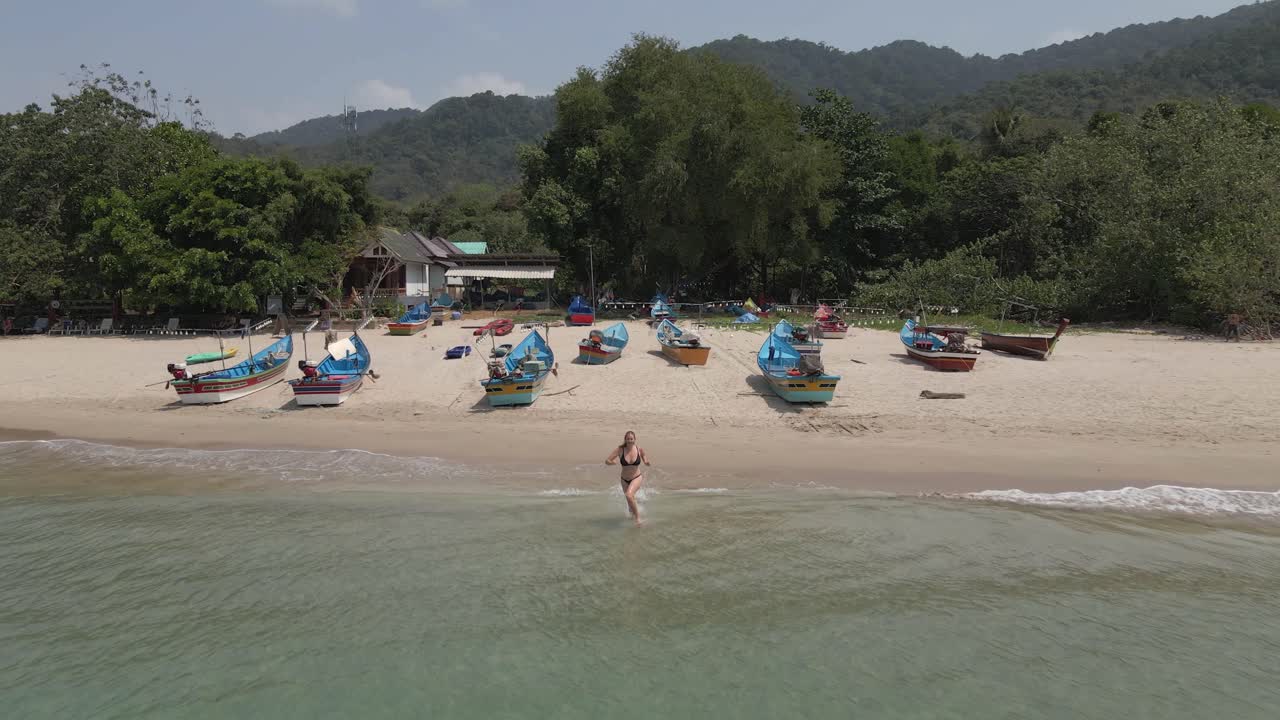 비키니 입은 아름다운 여성이 해변을 뛰어다니며 바다로 뛰어든다.