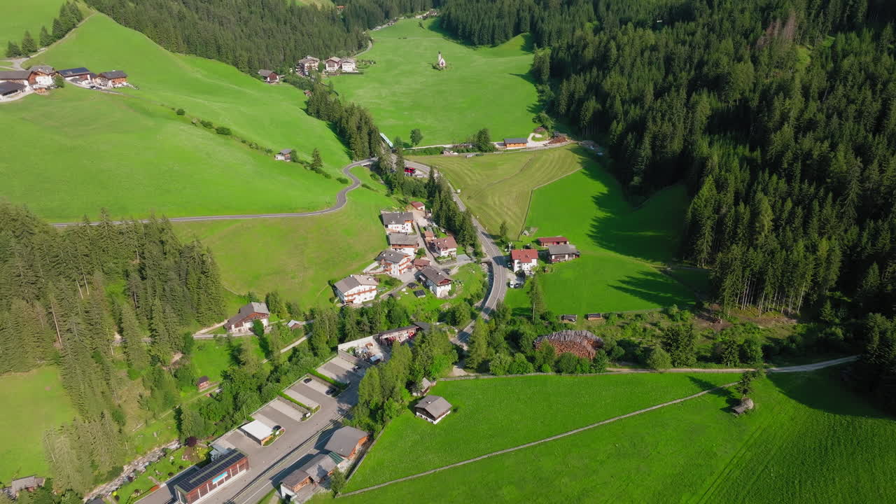 Slow drone reveal shot of the idyllic Church of St. John nestled in the blossoming landscape of the Italian Dolomites during spring