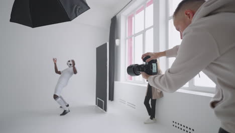 a sporty black male model poses for advertising posters. he plays with the ball for spectacular shots. stylish fashionable sports magazine. a photo shoot made with professional equipment in the studio