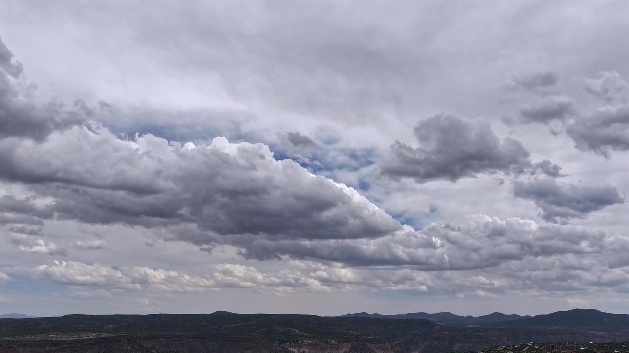 Sweeping drone 4K timelapse capturing dramatic morphing clouds rolling over a vast southwest canyon range. Atmospheric shifts in light reveal a beautifully rugged, majestic desert wilderness.