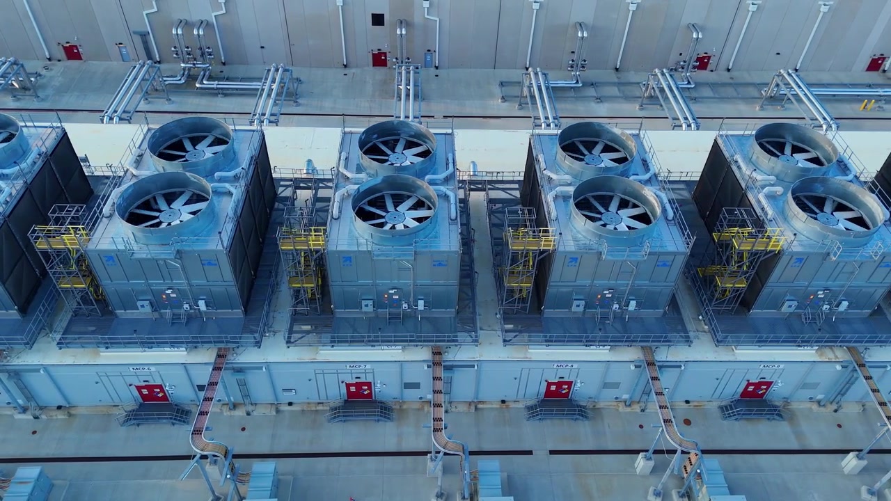 Industrial air conditioning units with spinning fans on the roof of a data center building