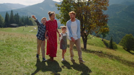 Family-enjoying-nature-walking-on-mountain-hill.-Parents-children-going-on-grass