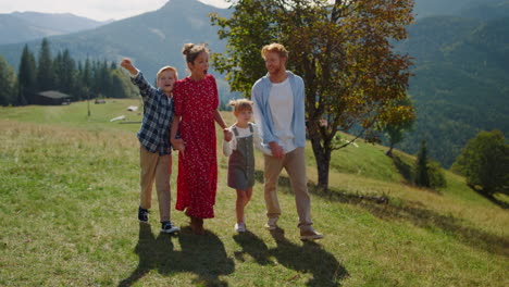 family enjoying nature walking on mountain hill. parents children going on grass