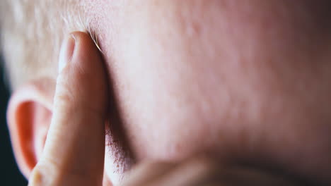 man puts and raises index finger on temple near grey hair