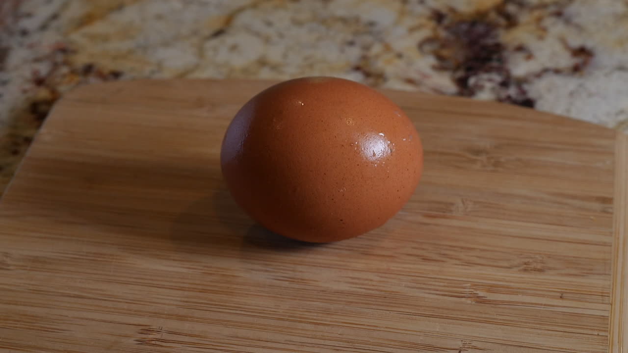 Brown egg on top of a wooden cutting board