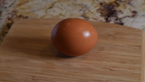 brown egg on top of a wooden cutting board