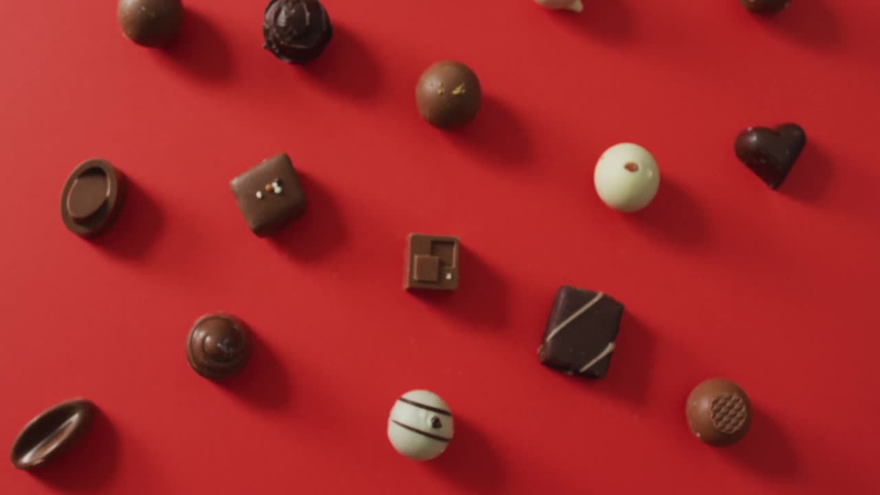 Premium stock video Black and white chocolates on red background at