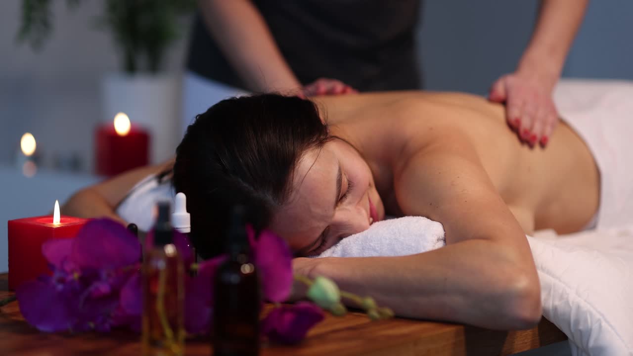 Professionel massør giver terapeutisk rygmassage til kvinde i spa.