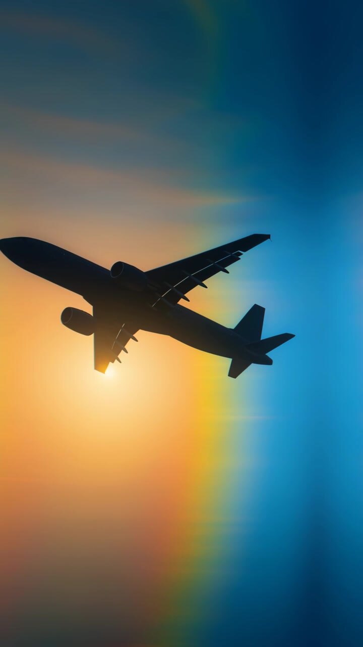 Airplane Silhouette Flying Through Vibrant Sunset Sky with Lens Flare