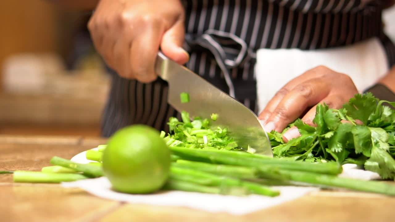 Chopping cilantro and adding lime and green onions for a flavorful Mexican relish - isolated slow motion