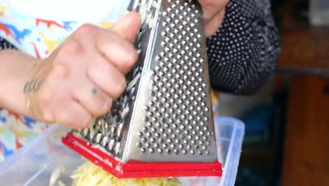 mujer rastrillando queso con un rastrillador de mano