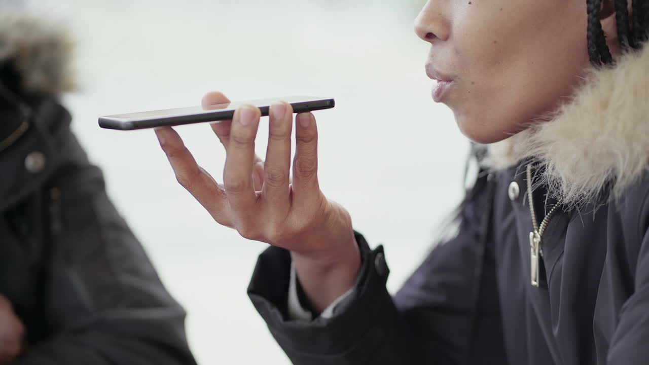 Afro-American young girl with braids and Afro-American middle-aged man in jacket with fur hood sitting outside