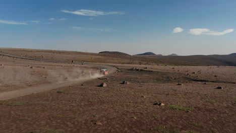 Drone-Con-Vista-Aérea-Siguiendo-A-Un-Camión-Que-Levanta-Una-Gran-Nube-De-Polvo-Mientras-Acelera-A-Lo-Largo-De-La-Carretera-Del-Desierto.-Coche-A-Vista-De-Pájaro-Que-Viaja-Por-El-Camino-Del-Desierto-Descubriendo-Partes-Deshabitadas-De-Islandia.-Concepto-De-Libertad