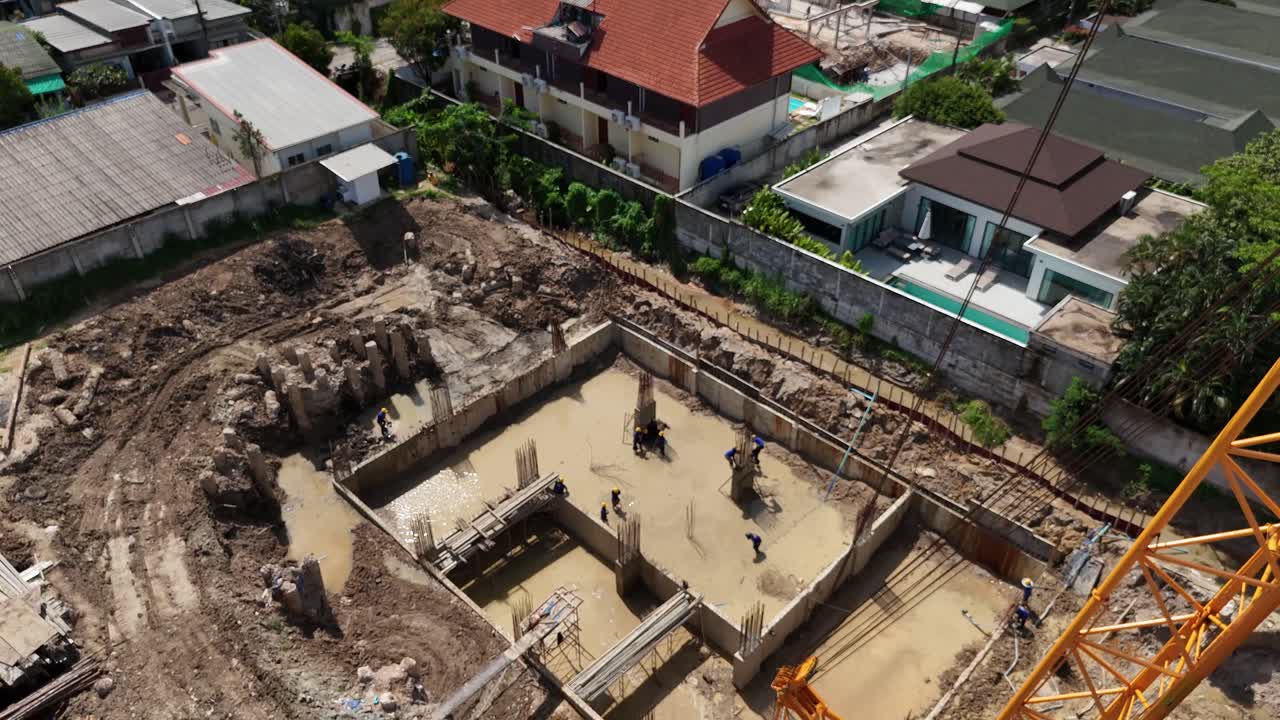 Aerial view of a construction site with workers and a crane building foundations