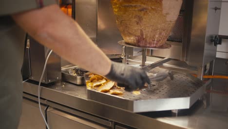 chef cortando carne de kebab doner en una saliva giratoria en una tienda de comida rápida, primer plano