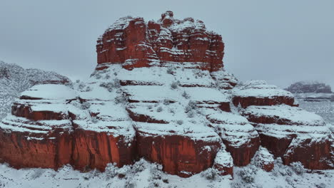 red rock formation covered with snow in sedona, arizona in winter - aerial drone shot