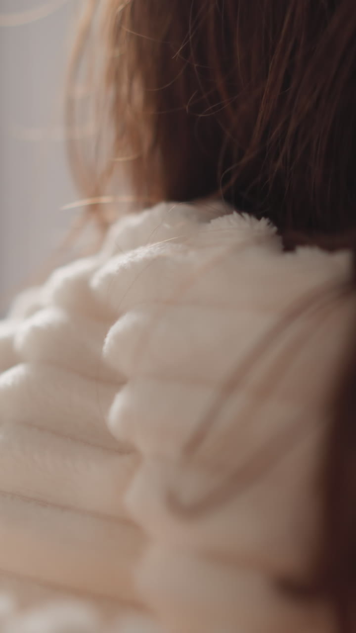 persona usa túnica de peluche procedimiento de fabricación en la ducha. mujer morena corre mano con dispositivo eléctrico sobre la cara en el baño moderno vista trasera cámara lenta