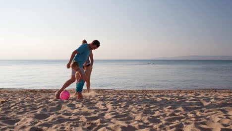 Familia-Joven-Jugando-Al-Fútbol-En-La-Playa