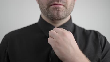 man in black shirt adjusts his tie