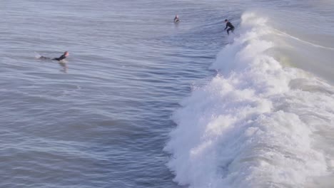 dos surfistas intentan atrapar una ola, el primero no lo logra, mientras que el segundo tiene mejor suerte