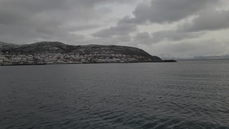 Flying-Towards-Skjervøy-Town-In-Troms-og-Finnmark-County,-Norway-During-A-Cloudy-Day-In-Winter---aerial-drone-shot