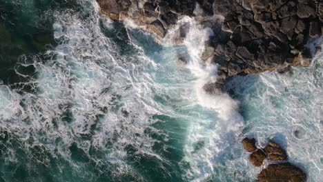 aerial view of waves crashing against rocky coastline
