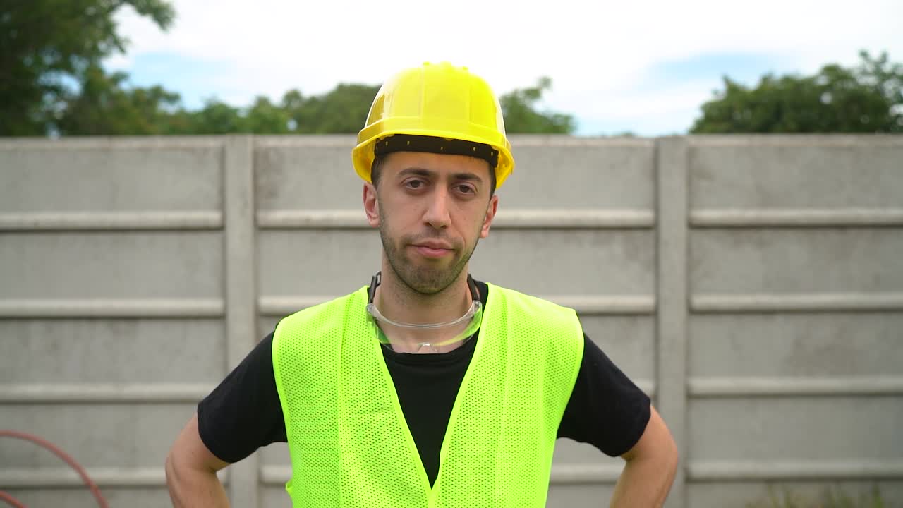 retrato frontal de un trabajador mirando a la cámara, con casco duro y chaleco de seguridad reflectante